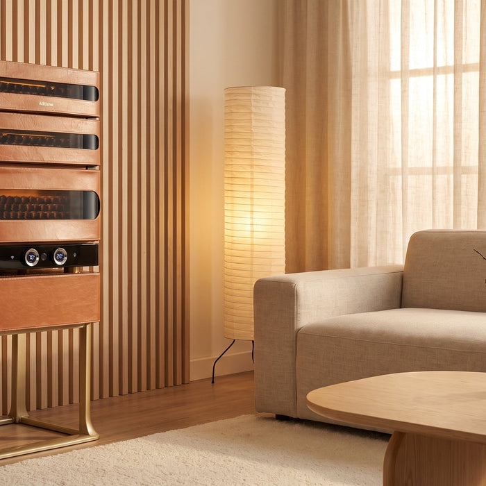 Afidano L3 Artistry cigar humidor in cognac leather on its gold stand in a warm minimalist living room