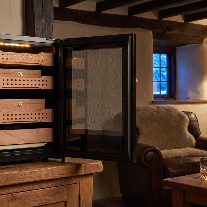 Afidano B1 compact cigar humidor open on an oak sideboard in an alpine chalet snug, Spanish cedar trays inside