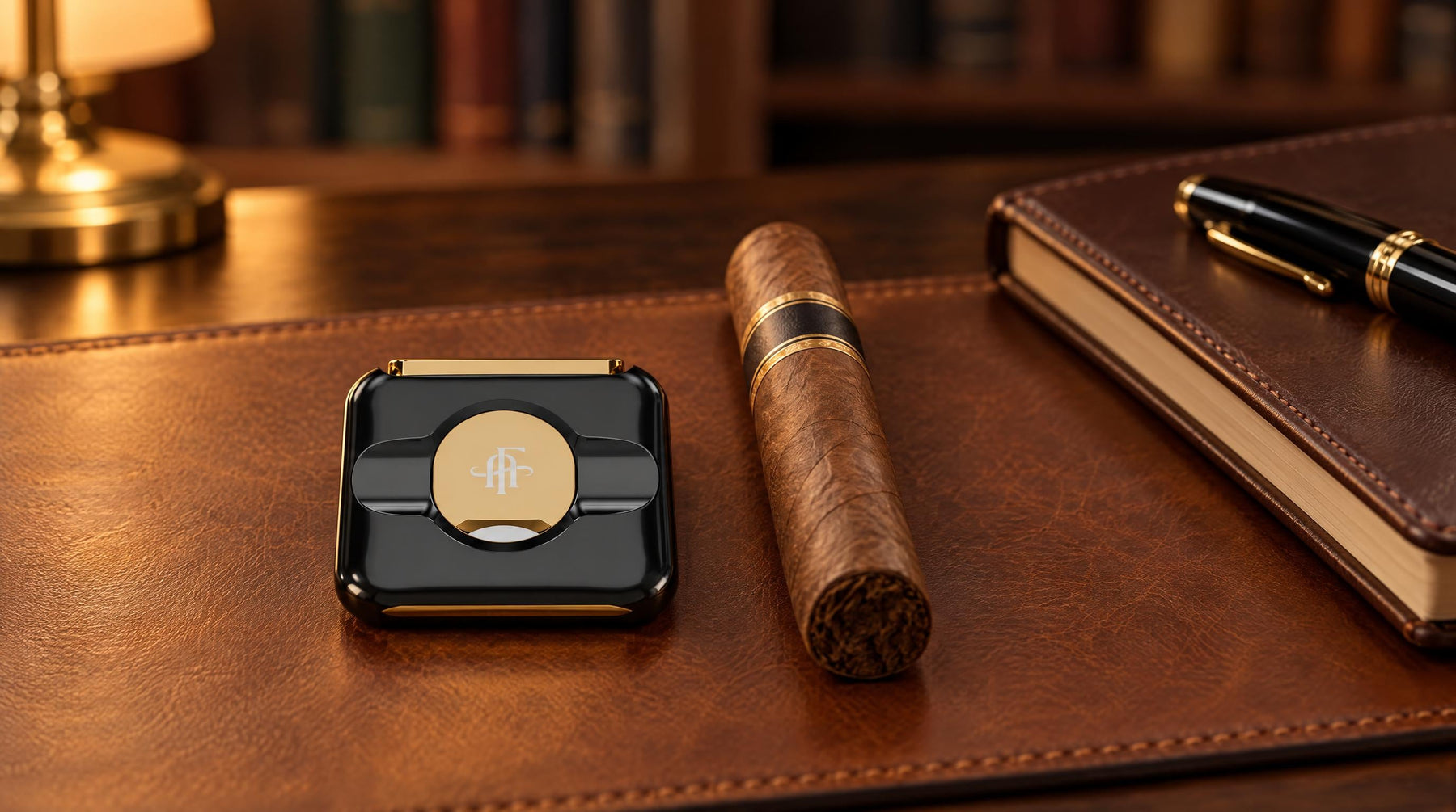 Afidano luxury stainless steel cigar cutter in black and gold on a leather desk blotter beside an unlit cigar