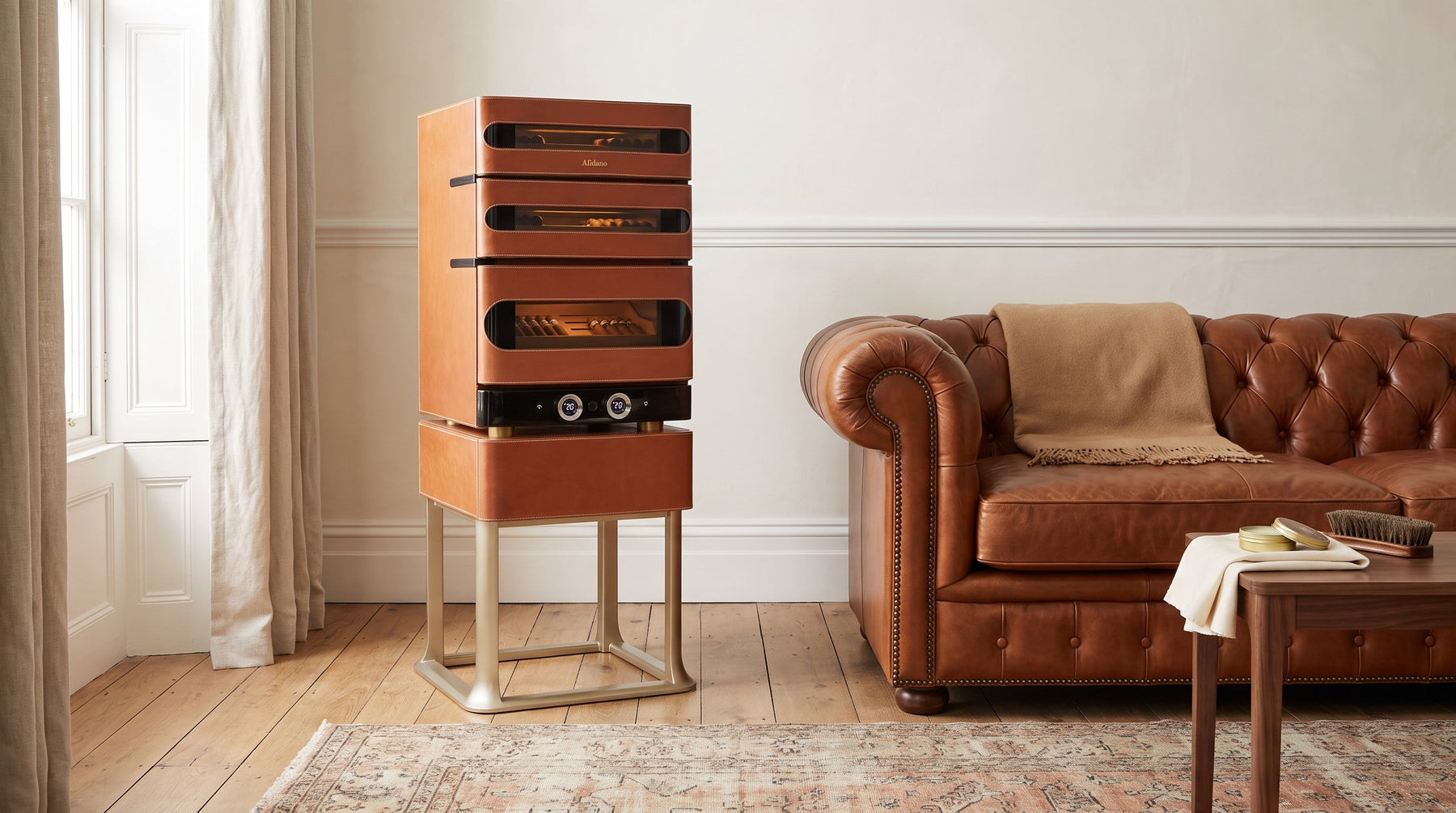 Afidano L3 Artistry cognac leather cigar humidor beside a Chesterfield sofa in a bright drawing room with leather care balm